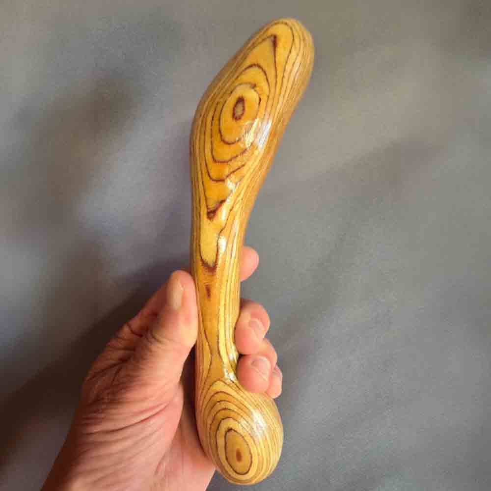 Handgefertigtes Holzunikat mit geschwungener Form und auffälliger, konzentrischer Maserung, in der Hand gehalten.